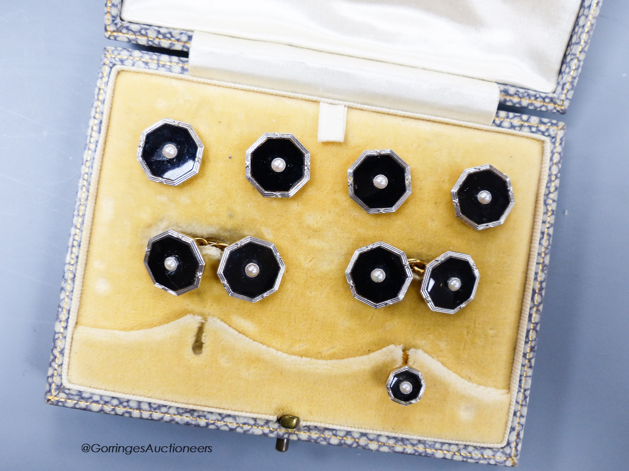 A cased 18ct, plat, black onyx and seed pearl set octagonal seven piece (ex eight) dress stud set, gross 13.8 grams.